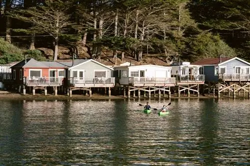 Два каякера на воде перед коттеджами Nick's Cove в заливе Томалес, Калифорния.
