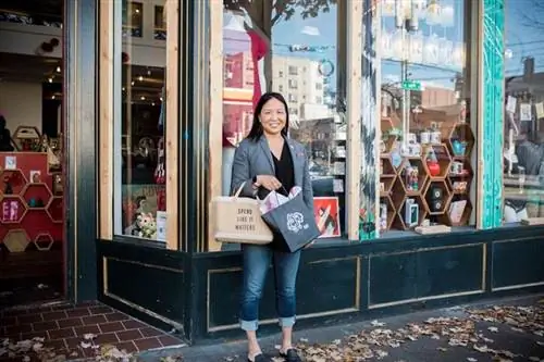 Женщина, стоящая возле магазина с сумками для покупок