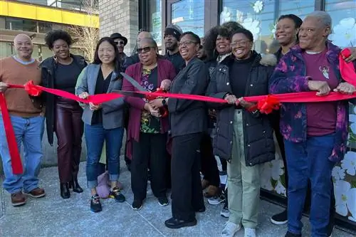 Группа женщин перерезает праздничную ленту возле магазина