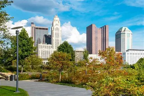 Вид на город Колумбус со стороны Национального мемориала ветеранов и музейного парка. Здесь есть извилистая пешеходная дорожка и пышная зелень, обрамляющая сцену. Это прекрасный день голубого неба.