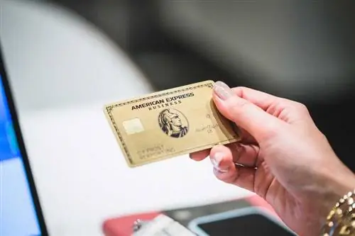 Женская рука держит золотую карту Amex