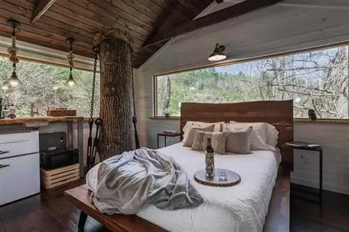 Кровать внутри домика на дереве в глэмпинге в Эшвилле.