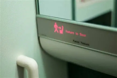 Крупный план светящейся таблички "Возвращение на место" в туалете самолета