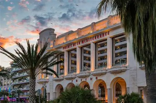 Пальмы и знаменитый отель Palais de la Mediterranee в стиле ар-деко и казино Hyatt на Английской набережной на закате