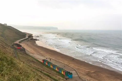 Вид с воздуха на цветные хижины вдоль берега Уитби-Сэндс в Северном Йоркшире, Англия.