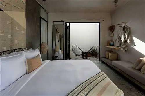 Деталь спальни Drift Hotel в Сан-Хосе-дель-Кабо с минималистичным дизайном и натуральными текстурами, такими как дерево, плетеные корзины и бетон.
