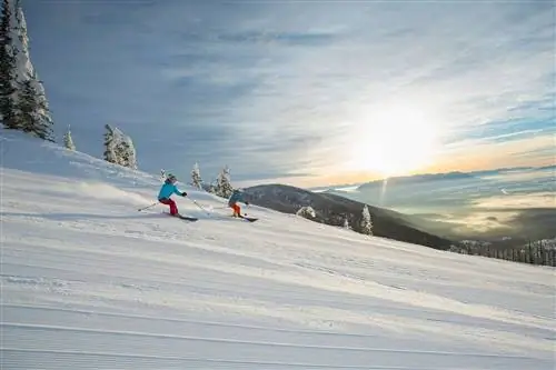 Пара катается на лыжах на закате на горе Уайтфиш