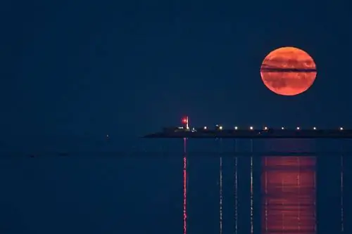 Редкая летняя полностью голубая осетровая Луна, восходящая над ирландским небом между маяками Дун Лаогэр 23 августа 2021 года, вид с пляжа Сэндимаунт, Дублин, Ирландия.