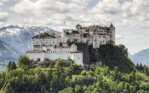 Зальцбург, Австрия: Крепость Хоэнзальцбург в Зальцбурге, Австрия, с горным хребтом Альп, возвышающимся на расстоянии. Построенный в течение нескольких сотен лет (с 11 по 16 века), он является одним из крупнейших средневековых замков в Европе длиной 250 м (820 футов).