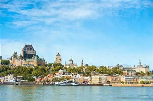 Панорамный вид на город Квебек со знаменитым и культовым отелем Chateau Frontenac и рекой Святого Лаврентия на фоне ясного неба.