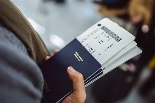 Руки женщины с паспортами и посадочными талонами во время ожидания на стойке регистрации в аэропорту