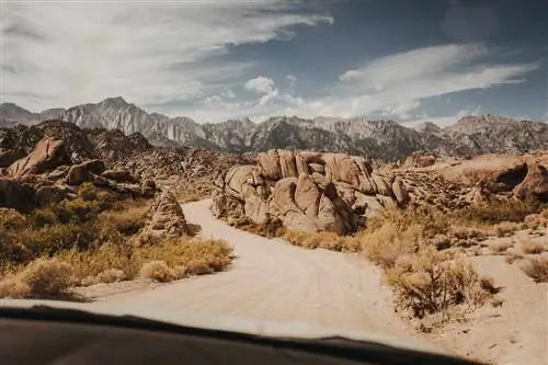 Вид через лобовое стекло автомобиля на гравийной дороге через Лоун-Пайн (Алабамские холмы) в Сьерра-Неваде, Калифорния.