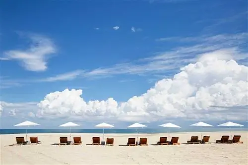 Шезлонги и зонтики на курорте Four Seasons в Лос-Кабосе на фоне голубого неба и пушистых белых облаков