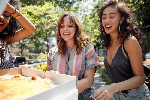 Молодые женщины тусуются в городе и едят пиццу