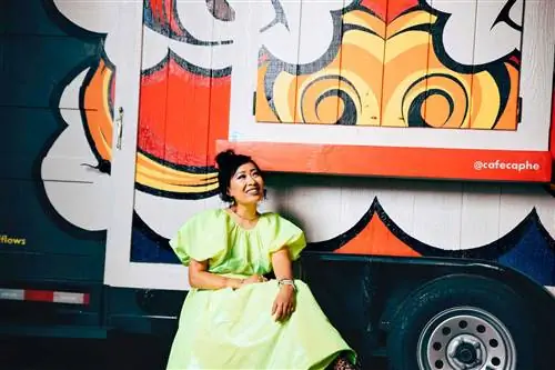 Владелица кофейного фургона Джеки Нгуен сидит перед своим красочно раскрашенным фургоном.