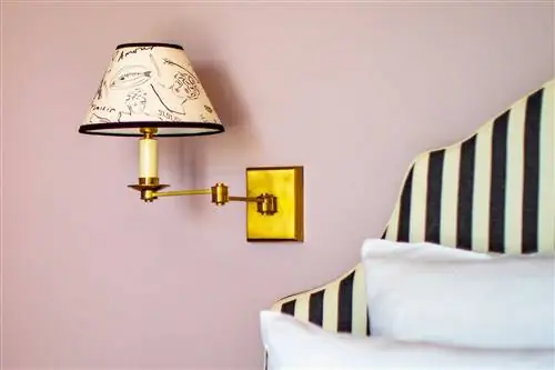 Деталь полосатого изголовья, подушек и бра с принтом в парижском отеле.