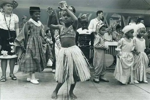 Ребенок в юбке из травы, раскачивающийся в такт оркестру калипсо; Чандра Галассо; 7; был одним из 10 молодых людей, танцевавших вчера на фестивале Caribana '67 в Центр-Айленде. Тысячи приняли участие в проекте столетия Канады в Вест-Индии.