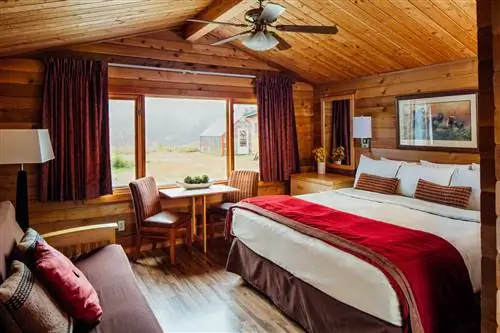 Внутренняя комната в Denali Backcountry Lodge с кроватью и стулом и видом из окна.