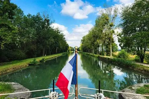 Французский флаг на лодке, проходящей через шлюз недалеко от Бразей-ан-Плен, Франция.