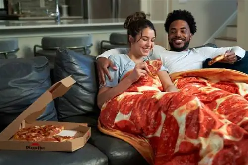 Пара обнимается с пиццей под одеялом для пиццы