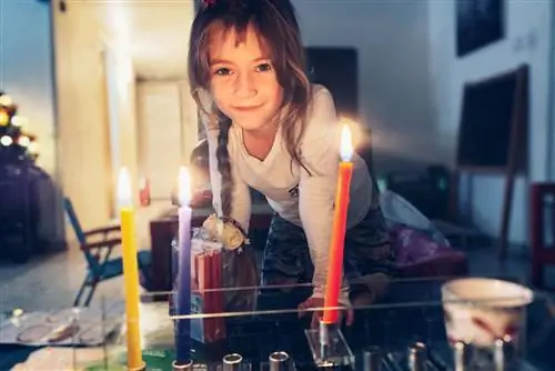 Маленькая девочка зажигает менору дома