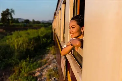 Улыбающаяся женщина смотрит в окно поезда Улыбающаяся женщина смотрит в окно поезда