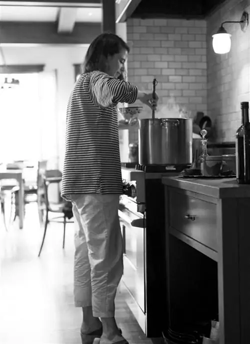 Фанни Сингер стоит у плиты и готовит куриный бульон в большой кастрюле.