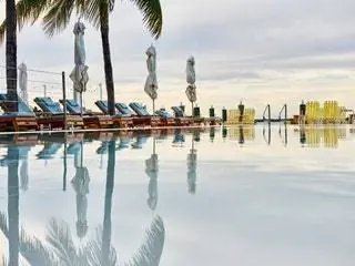 Это изображение может содержать Summer Arecaceae Palm Tree Plant Water Building Waterfront Tropical Hotel and Pool