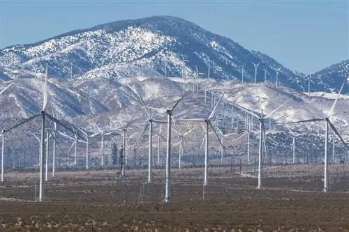 Банк белых ветряных мельниц перед заснеженными горами в Мохаве, Калифорния