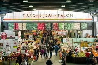люди ходят по крытому продовольственному рынку. Вывеска Marché JeanTalon выше