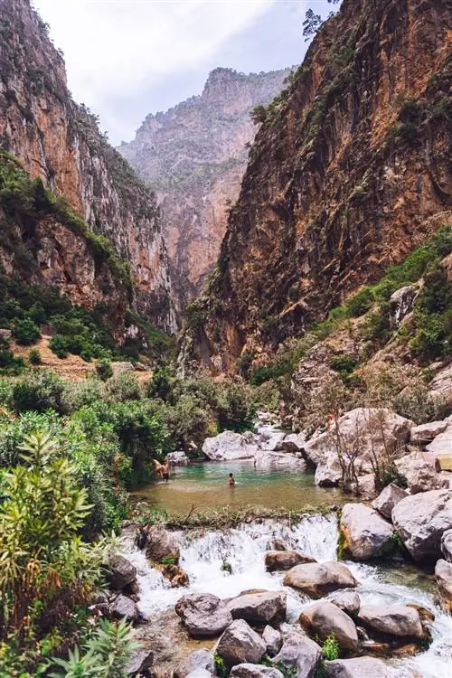 двое мужчин в водоеме. Каменистая местность. Горы выше.