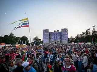 Это изображение может содержать символ и флаг фестиваля Дэвида Уорролла в толпе людей.