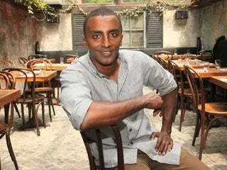 На изображении может находиться Marcus Samuelsson Мебель Стул Человек Человек Ресторан Кафе Стол Столешница и Сидение