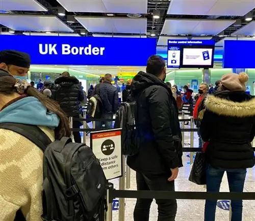 Путешественники в масках стоят в очереди на пограничном контроле Великобритании