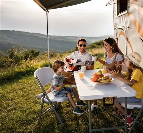 Семья ест, улыбаясь возле автофургона