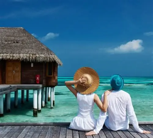 Пара сидит на променаде на Мальдивах и смотрит на океан