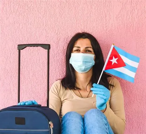 Турист с флагом Кубы в маске и багаже