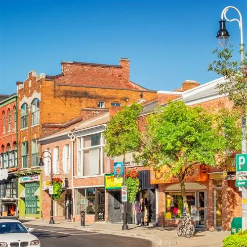 Автомобиль проезжает мимо магазинов в центре города Сент-Катаринс, Онтарио, Канада, в солнечный день