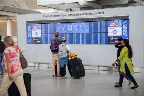 Люди смотрят на табло статуса рейса в терминале 1 международного аэропорта Пирсон, Торонто, Онтарио, Канада