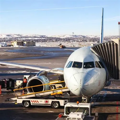 Наземная команда загружает багаж, а пилоты готовят самолет Air Canada к взлету на взлетной полосе международного аэропорта Калгари.