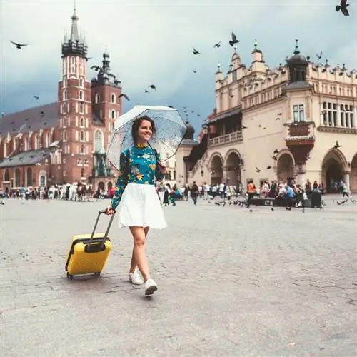 индивидуальный путешественник с зонтиком и чемоданом в старом городе Краков, Польша