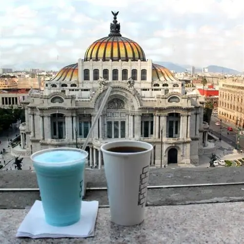 Панорамный вид на Дворец изящных искусств в Мехико с чашкой кофе и синим напитком в кадре