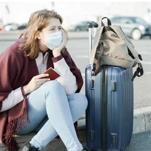 Расстроенная путешественница с европейским паспортом, сидя в пункте сбора в аэропорту со своим багажом