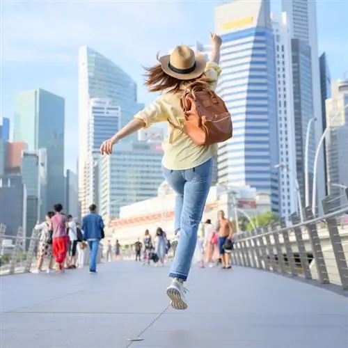 Молодая путешественница прыгает от счастья во время городского отпуска в Сингапуре, Юго-Восточная Азия