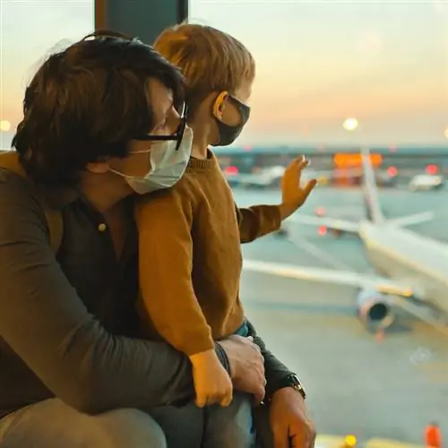 Отец и сын в масках ждут своего рейса