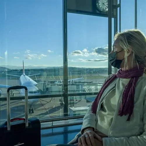 Женщина в аэропорту ждет рейса в маске