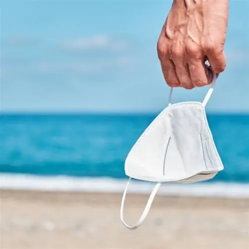 Человек с маской в руке на пляже