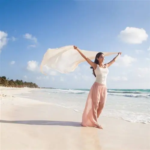 Туристка держит розовую надувную шезлонг, направляясь в океан в Канкуне, Мексика