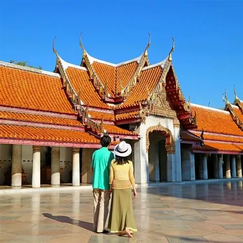 Пара путешественников, исследующих храм в Таиланде