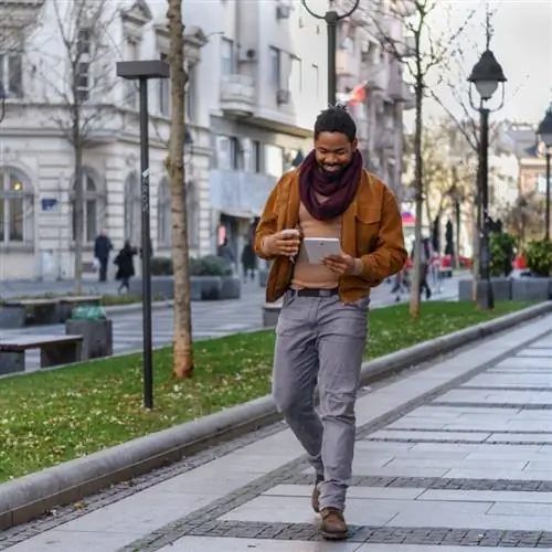 Молодой турист с планшетом в руках улыбается во время прогулки по улицам Белграда, Сербия